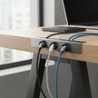 Magnetic Cable Organizers attached to desk edge keeping USB-C charging cables organized and accessible
